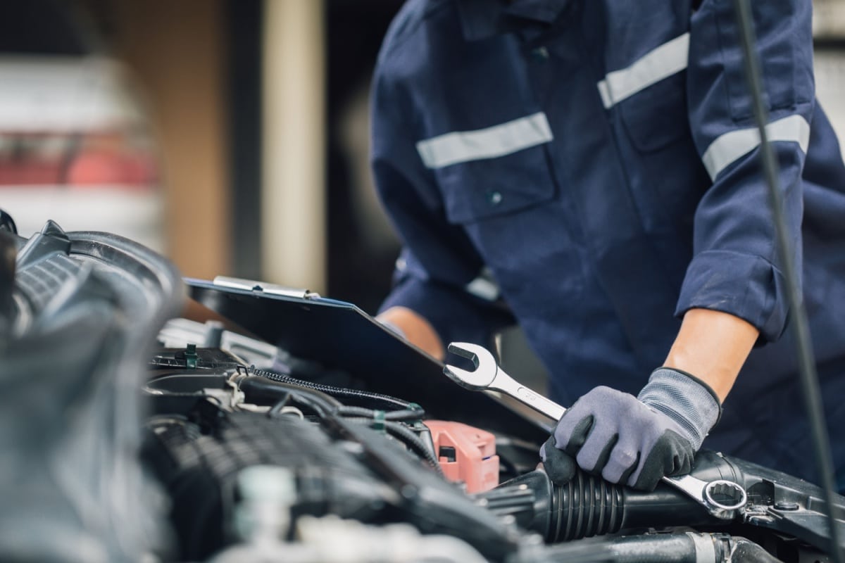 Person bruker skiftenøkkel i motorrommet på en bil