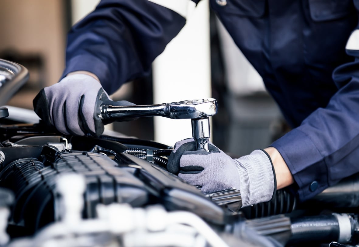 Mekaniker bruker skralle i motorrommet på en bil